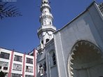 Foto da entrada da primeira mesquita brasileira (Mesquita Brasil, na Avenida do Estado, cidade de So Paulo). Um elemento comum s mesquitas  o minarete, uma torre alta e delgada geralmente situada num dos cantos da estrutura da mesquita. O minarete  geralmente o ponto mais alto da mesquita e muitas vezes o ponto mais alto na rea onde a mesquita se situa. O minarete mais alto do mundo  o da Mesquita Hassan II em Casablanca, Marrocos. As primeiras mesquitas no eram detentoras de minaretes. Alguns movimentos conservadores do islo, como o Wahhabismo, evitam colocar minaretes nas mesquitas, por considerarem-nos uma forma de ostentao. O primeiro minarete foi construdo em 665 em Bassora, durante o reinado do califa omada Muawiyah I. Este califa estimulou a construo de minaretes por influncia das torres das igrejas crists. Os arquitetos islmicos copiaram este elemento das igrejas e utilizaram-no com a mesma finalidade: chamar os crentes  orao.  atravs do minarete, cuja altura superior s casas que o rodeiam tem a funo prtica de fazer chegar mais facilmente aos fiis a voz do muezim que os chama para as cinco oraes dirias. s vezes, numa ou outra oportunidade, os minaretes assumiram tambm uma funo simblico-poltica, como a de afirmao da superioridade do Isl sobre as outras religies. Em muitos pases onde os muulmanos no constituem a maioria da populao, as mesquitas no esto autorizadas a emitir em tom alto a chamada  orao (adhan). Com o avano da tcnica, ultimamente, esto sendo usados alto-falantes, ainda mais quando a mesquita se encontra no meio de bairros no muulmanos e os muezins aproveitam desse instrumento para alongar suas oraes. Em outros casos, comearam a ser usadas gravaes da chamada  orao. Essas inovaes so contrrias  tradio muulmana ou sunnah e os pases islmicos mais rigorosos condenam a prtica. No Egito, o uso dos alto-falantes est limitado a dois minutos e proibido na primeira orao do dia. Nas mesquitas onde no existe o minarete o muezim faz o apelo dentro da mesquita ou no exterior do edifcio. <br> <br> Palavras-chave: mesquita, So Paulo, minarete, islamismo, paisagem religiosa, muulmano, arquitetura, sagrado.